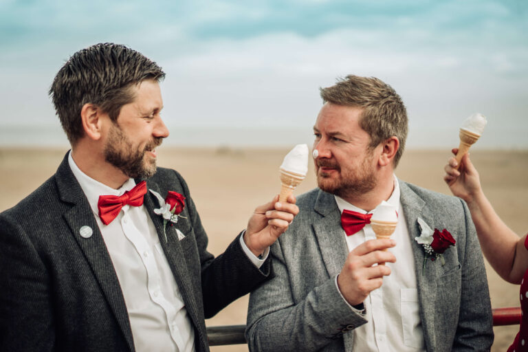 A groom dabs ice cream on his new husband's nose as they stand by the beach at Chapel St Lenards after their elopement ceremony