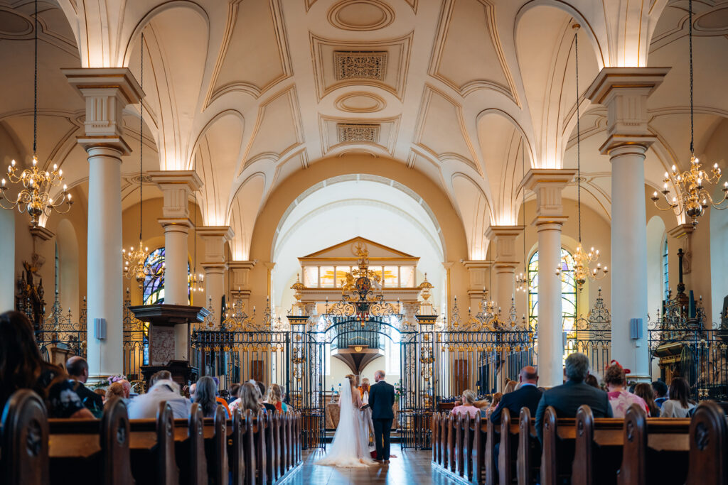 A wide view of a wedding at Derby Cathedral with ornate ceiling and pillars