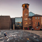 A boy picks up confetti in front of Derbyshire wedding venue, Derby Museum of Making with a soft sunset sky