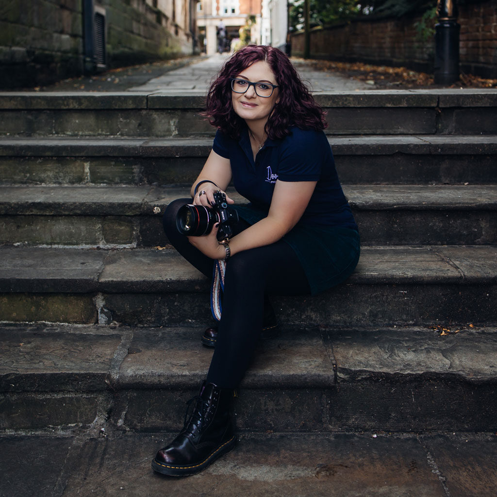 Wedding photographer Emma Duder sits on the steps near the cathedral in her home town of Derby holding her camera
