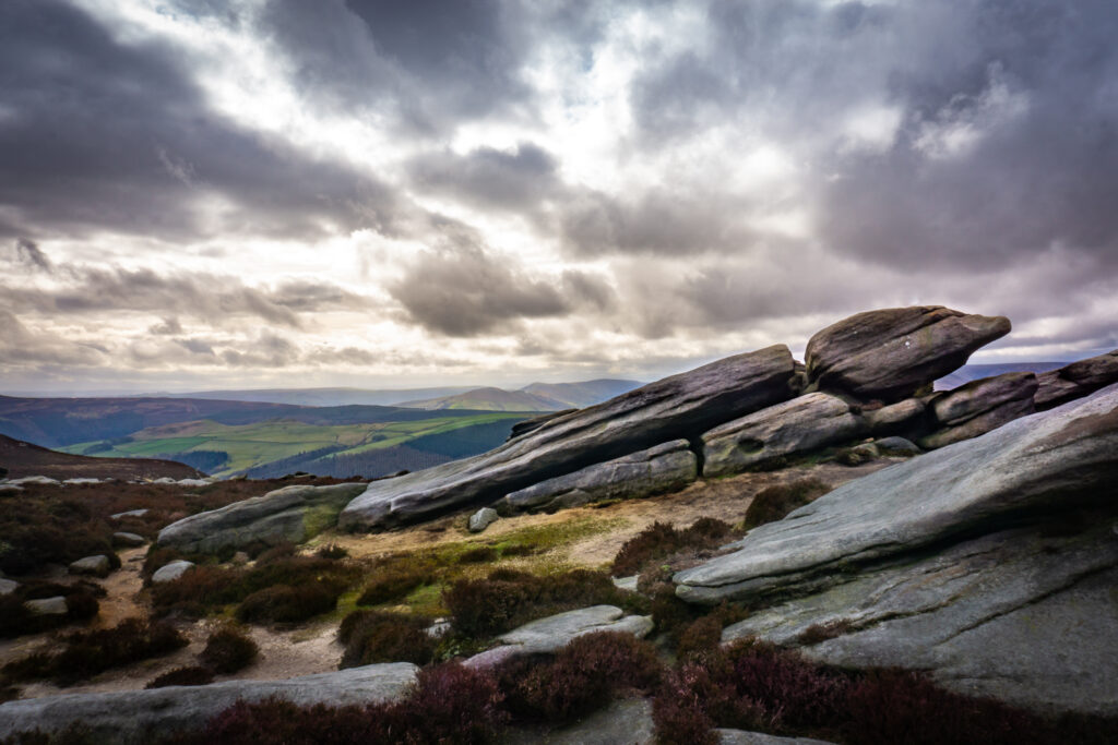A view over the Derwent Valley from Derwent Edge with rocks in the foreground and a moody sky