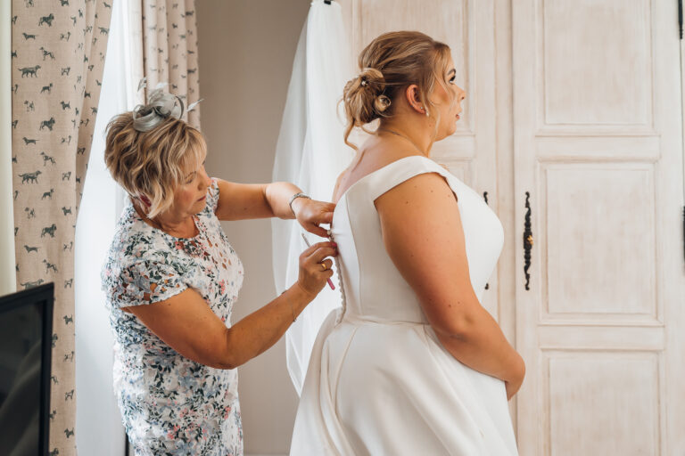 Mother of the bride does up her daughters dress diring getting ready photos at Kedleston Country House Hotel