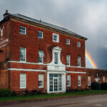 The exterior of Kedleston Country House, Derbyshire with a rainbow and stormy sky